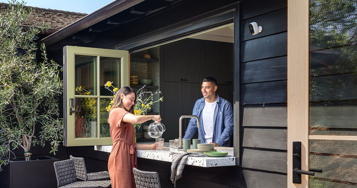 Happy couples and behind them Arlo Security Camera on the Wall in home